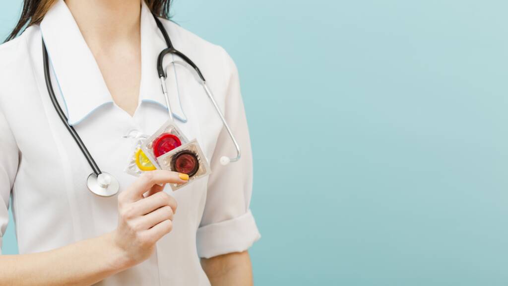 Médica exibe dois preservativos: os centros de saúde pública, clínicas de saúde sexual e hospitais são opções comuns onde as pessoas podem se submeter a testes.