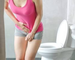 Mulher com infecção urinária perto de vaso sanitário: a infecção urinária não é contagiosa e não se transmite de uma pessoa para outra