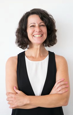 Mulher sorri tendo os braços cruzados: um assunto muito importante para as mulheres é a saúde urinária na menopausa, fase natural da vida marcada pela redução progressiva da produção de hormônios, especialmente o estrogênio