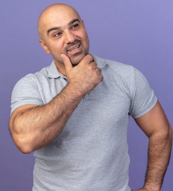 Homem careca sorri ao fazer pose pensativa: a alopecia androgenética é a forma mais comum de queda de cabelo no homem adulto e afeta, em diferentes graus, cerca de metade dos homens acima dos 50 anos